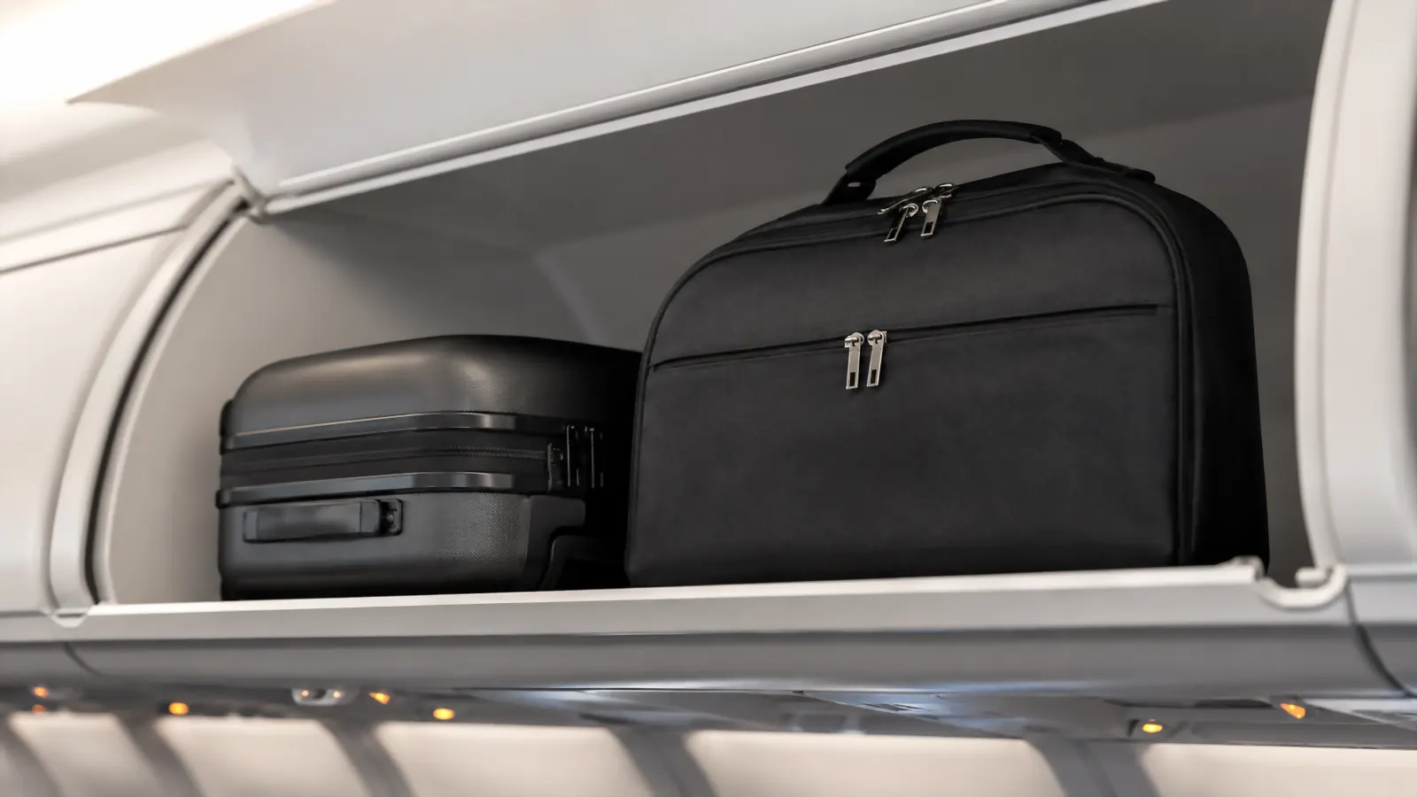 Rolled Lazebox garment bag standing upright inside an open overhead bin on a plane