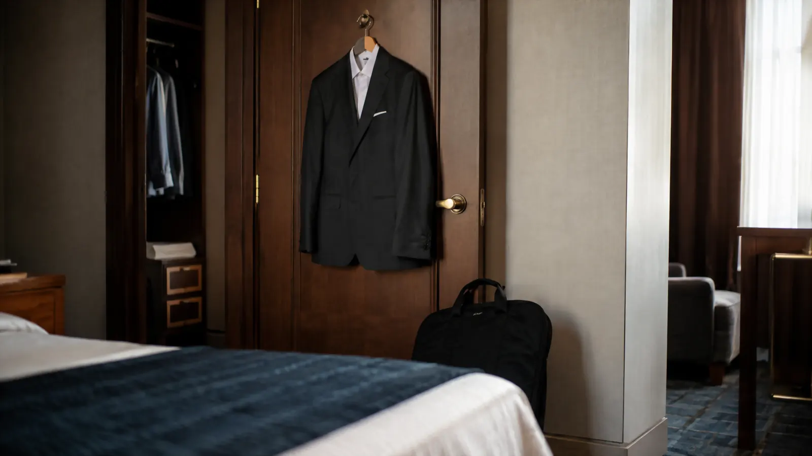 Traveler hanging a pressed suit from a garment bag on a hotel closet door before a meeting
