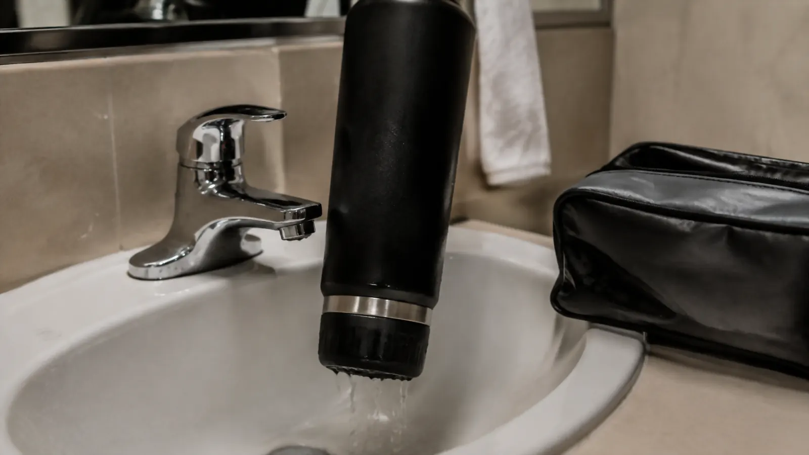 The tumbler sitting empty and upside down in a hotel bathroom sink mid-rinse