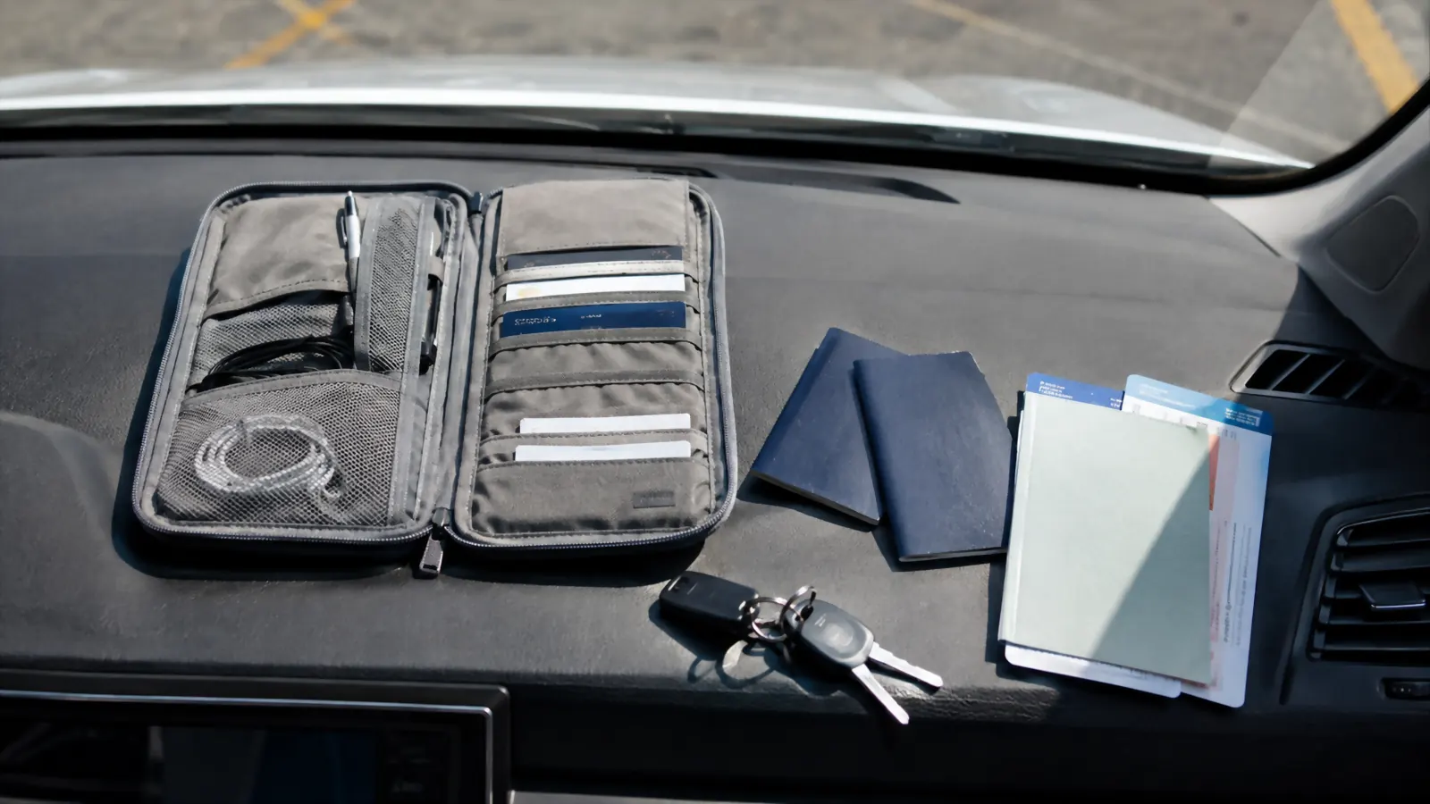 Two kids' passports and a family document organizer spread on a rental car dashboard