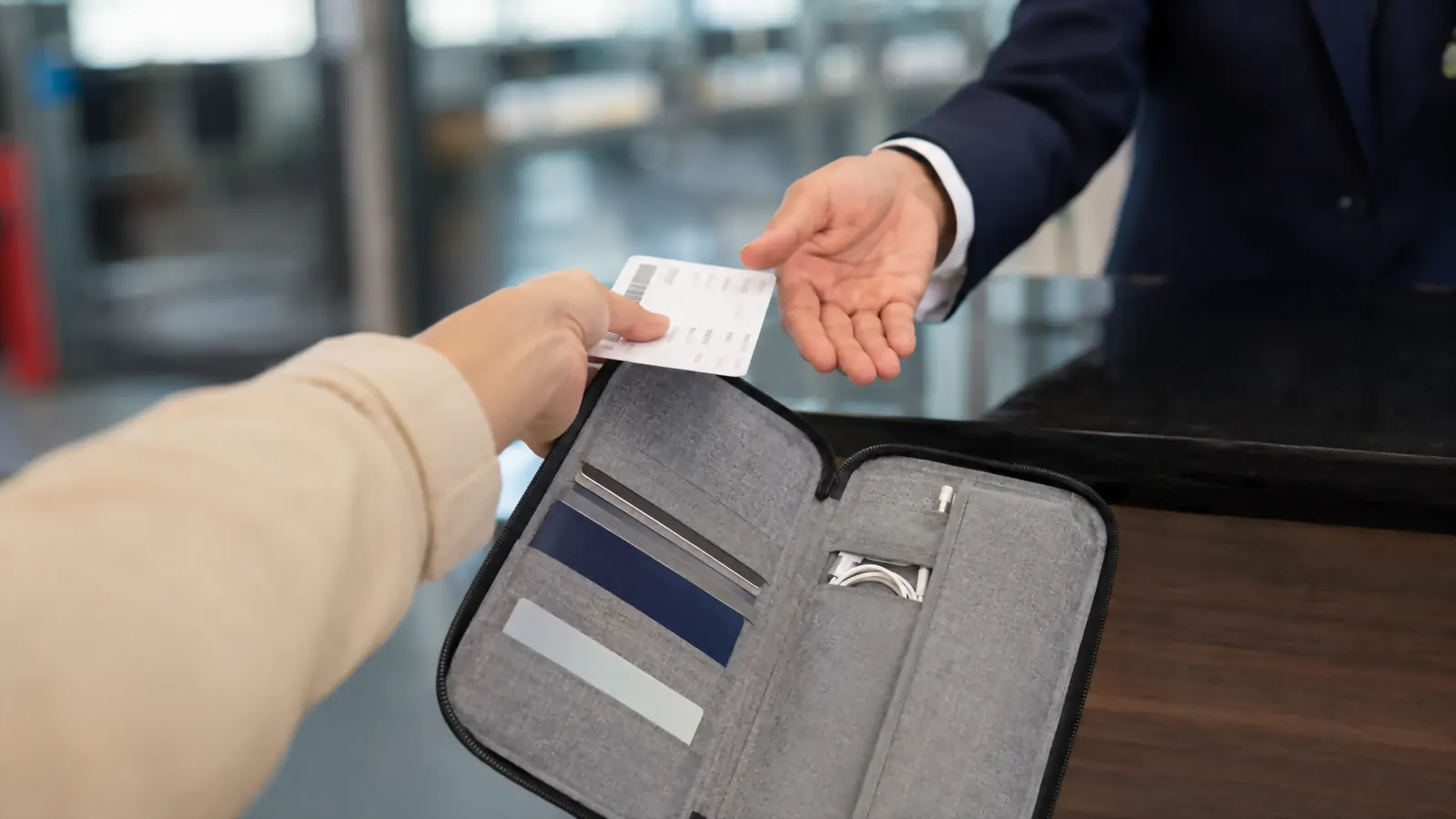 Hand pulling a boarding pass out of the gray Valante organizer at a departure gate counter